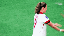 two female soccer players are hugging each other on a field .