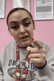 a woman wearing a hello kitty lanyard points her finger