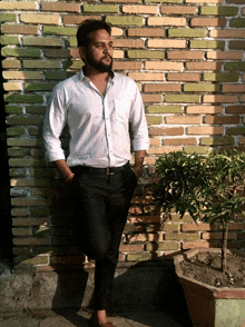 a man standing in front of a brick wall