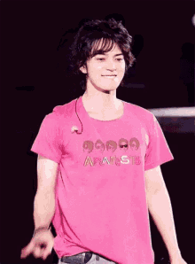 a young man wearing a pink t-shirt that says arashi is giving a peace sign