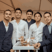 a group of men standing around a table with wine glasses and candles