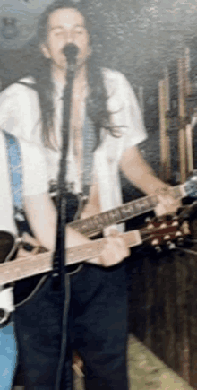 a man singing into a microphone while holding a guitar