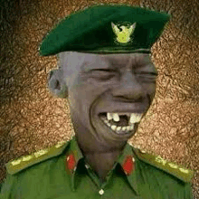 a man in a military uniform is laughing with his eyes closed and his teeth missing .