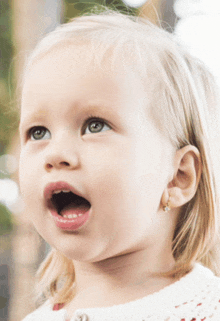 a little girl with earrings on her ear is looking up