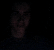 a man 's face is visible in the dark and he is smiling .