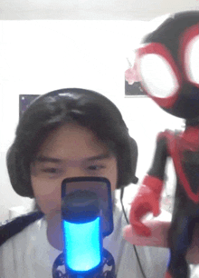 a person wearing headphones is holding a microphone in front of a toy spider-man