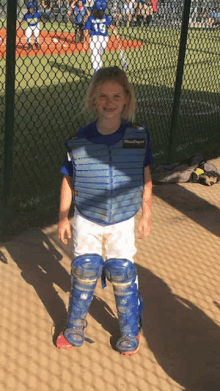 a little girl is wearing a blue catcher 's uniform