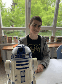 a young boy wearing a star wars shirt sits at a table