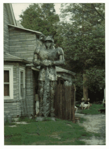 a statue of a knight with a sword in front of a brick building