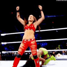 a woman in a red crop top is screaming in a wrestling ring .