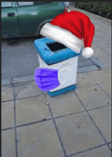 a santa hat is on a trash can with a mask on it