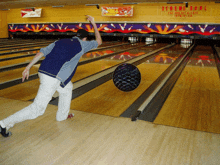 a man throws a ball in a bowling alley with a sign that says extreme bowl