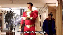 a man in a superhero costume is standing next to another man and says `` your phone 's charged . ''