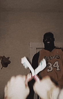 a man wearing a lakers jersey is holding a pair of toothbrushes