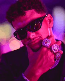 a man wearing sunglasses and a chain has a ring on his left hand that says ' king ' on it