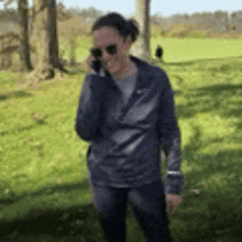 a woman is talking on a cell phone while standing in a field .