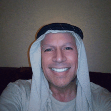 a man with a scarf around his head smiles