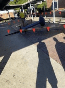 a shadow of a person is cast on the ground in front of a picnic table .