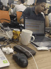 a man sits at a desk with a laptop and a can of beer on it