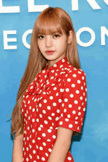 a woman in a red and white polka dot dress is standing in front of a blue wall .