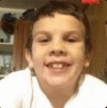 a young boy is smiling and making a funny face in a kitchen .