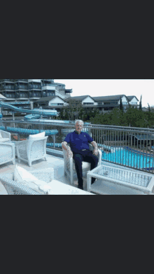 a man in a blue shirt sits in front of a pool