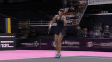 a woman in a blue dress is holding a tennis racquet on a court with a sign that says la region