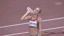 a woman is holding a bottle of water on a track while another woman holds a bottle of water .