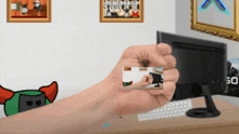 a hand is holding a card with a picture of a man playing a video game on it