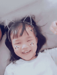 a little girl wearing a cat ear headband is smiling for the camera