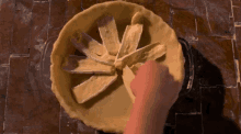 a person is making a pie with slices of cheese in the center