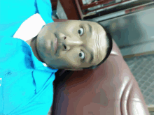 a man wearing a blue shirt is laying on a red couch