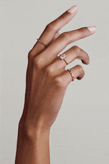 a woman 's hand is shown with several rings on it including an emerald cut diamond ring