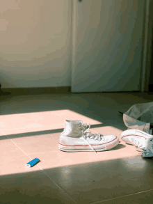 a pair of white converse shoes sit on a tile floor