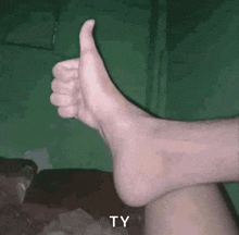 a person 's foot is giving a thumbs up sign with the letters ty below it