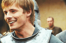 a man wearing a knight 's armor is smiling and looking to the side