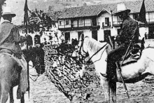 two men are riding horses in a black and white photo .