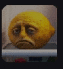 a lemon with a sad face is sitting on a shelf in a refrigerator .