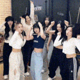 a group of young women are posing for a picture in a room with their arms in the air .