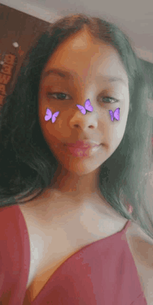 a girl with purple butterflies on her face is wearing a red dress