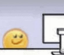 a yellow smiley face is sitting on a desk next to a computer monitor .