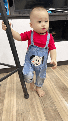 a baby wearing overalls and a red shirt