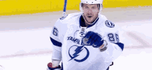 a hockey player wearing a white jersey with a lightning bolt on it is holding a puck on the ice .