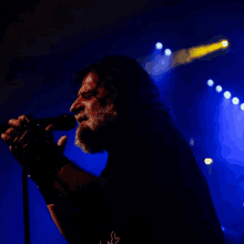 a man with a beard is singing into a microphone in the dark