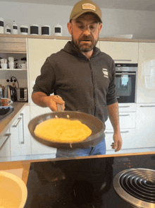 a man wearing a g-star sweatshirt is flipping a pancake on a stove