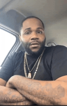 a man with a beard and a necklace is sitting in a car .