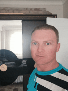 a man wearing a blue and white striped shirt stands in front of a mirror