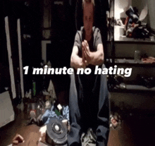 a man sits in a messy room with the words " 1 minute no hating " written above him