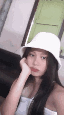 a young girl wearing a white bucket hat is taking a selfie .