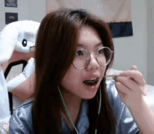 a woman wearing glasses is eating a spoonful of food .